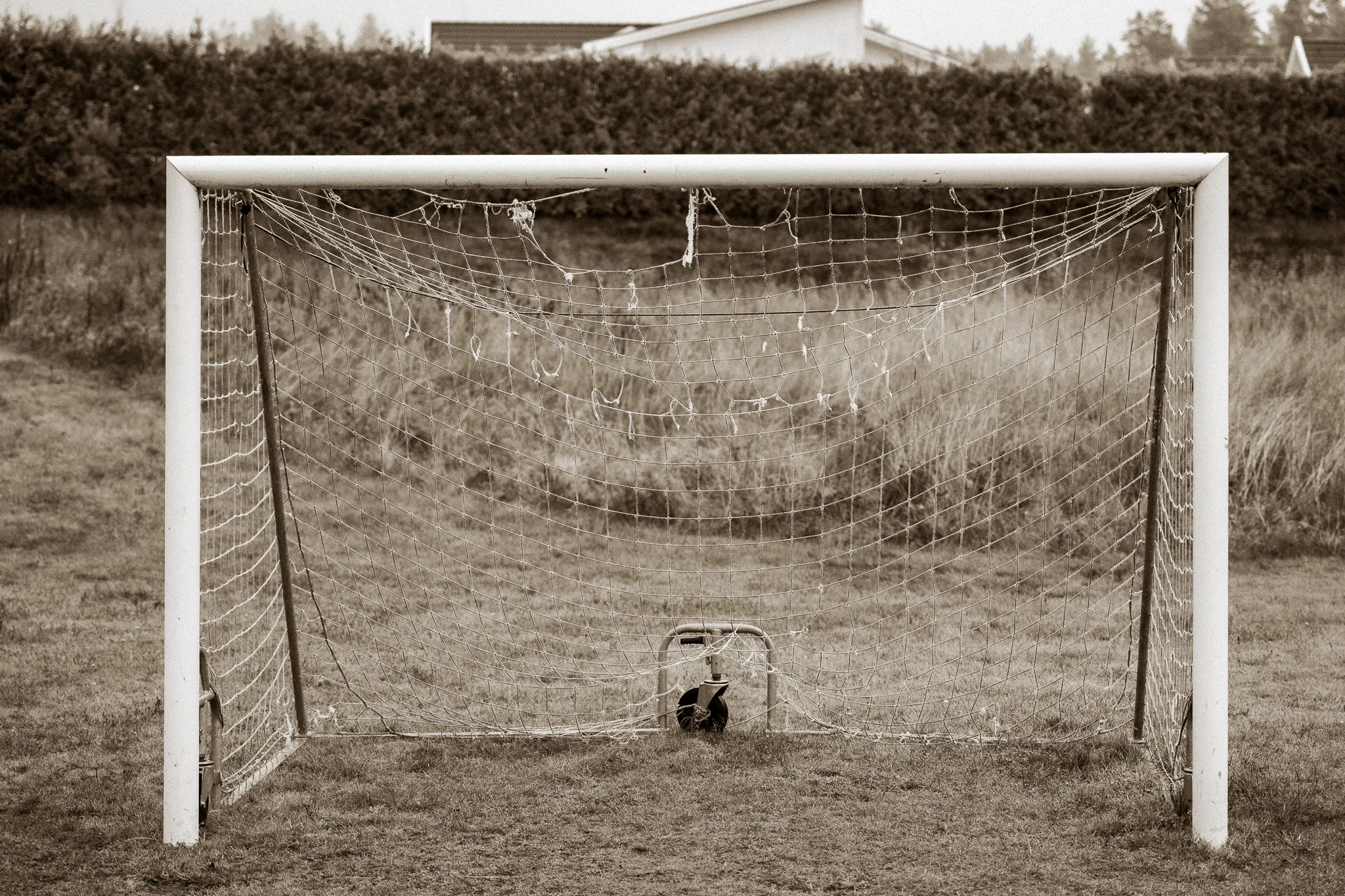 Worn football goal with a torn net in sepia